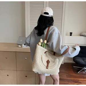 Detail of cream woven tote bag with brown leather shoulder strap and decorative front pocket