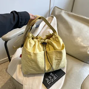 Grande borsa a secchiello in nylon beige con coulisse e tracolla larga su blazer