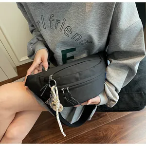 Detail of black crossbody bag with double zippers and decorative white woven rope zip puller