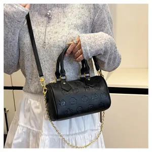 Détail du sac Boston noir avec motifs de dessins animés gaufrés et chaîne dorée