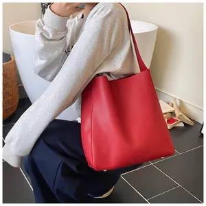 Dettaglio della borsa tote in pelle rossa con piedini protettivi e logo dorato stampato