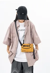 Dettaglio borsa a tracolla gialla con logo MIGE nero e tracolla regolabile sportiva