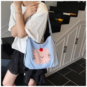 Close-up of light blue checkered canvas tote bag with a pink cartoon cat design