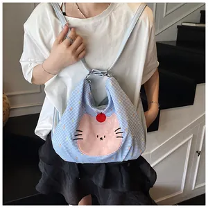Detail of light blue checkered tote bag with a pink cartoon cat patch and shoulder strap