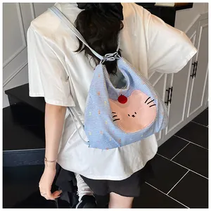 Detail of cute cat face patch and red pompom on blue gingham canvas tote bag back