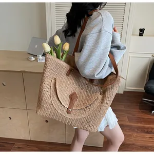 Detail view of large capacity straw woven tote bag with brown leather strap on shoulder