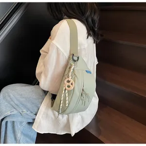 Detail of light green waterproof nylon crossbody bag with pretzel charm and wide strap