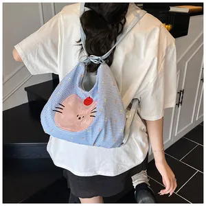 Detail showing blue checkered tote bag with pink cartoon cat patch and embroidery