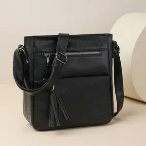 Borsa a tracolla retrò nera con cerniere multiple e lunga nappa su sfondo moderno
