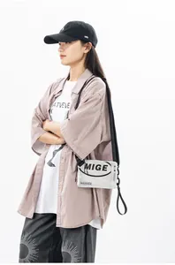Dettaglio della borsa a tracolla argento con scritta MIGE e tracolla in nylon nero