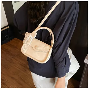 Creamy beige crossbody bag with lace bow accessory shown on a model's shoulder