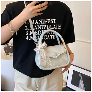 Detail of mint green mini handbag featuring a delicate white lace bow and round buckle