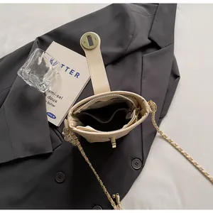 Détail du sac seau beige avec bandoulière chaîne et compartiments intérieurs organisés