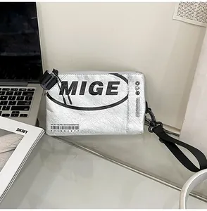 Dettaglio borsa metallizzata argento con logo MIGE e texture increspata su vetro