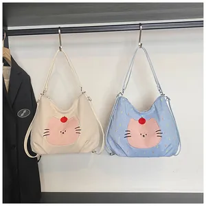 Detail of corduroy and plaid tote bags featuring cute pink cartoon cat embroidery
