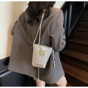 Sac seau tissé argenté avec bandoulière chaîne dorée et pompon sur mannequin
