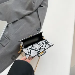 Borsa a tracolla chic con stampa a serpente, chiusura dorata e catena su tavolo