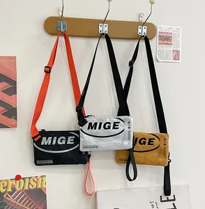 Tre colori di borse a tracolla con logo MIGE appese a ganci di legno a parete