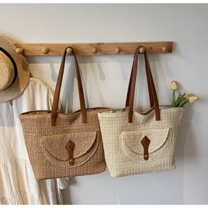 Detail of handwoven straw tote bag featuring wavy texture and brown leather shoulder straps