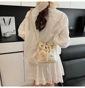 Detailed back view of embroidered bucket bag with pearl handle and golden chain