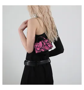 Mini borsa a tracolla rosa e nera con motivo a serpente e catena dorata su modella
