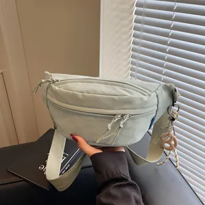 Light green canvas cross-body chest bag with multi-zipper layers and wide strap