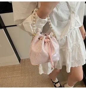 Detail of pink bucket bag with butterfly jacquard pattern and large pearl handle