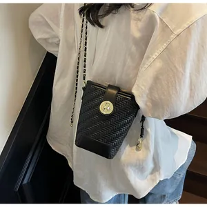 Détail du sac bandoulière tissé noir avec boucle anneau dorée et bandoulière chaîne