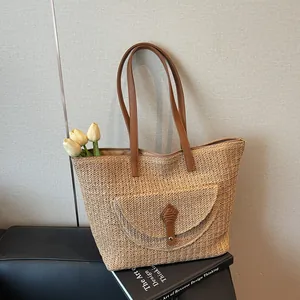 Minimalist straw woven tote bag with brown leather straps and decorative front pocket