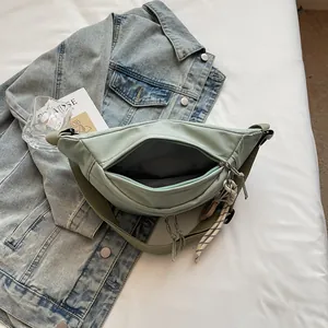 Mint green canvas chest bag with adjustable strap and spacious interior on blue denim
