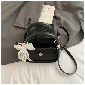 Elegant black minimalist handbag with a white lace bow detail and shoulder strap
