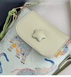 Detail of mint green brocade phone bag with elephant pattern and star button