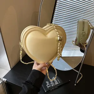 Sac bandoulière cœur jaune crème avec chaîne dorée et pendentif boule métallique chic