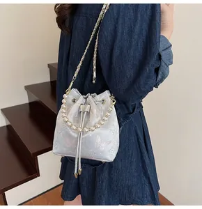 Detail of silver-grey bucket bag with pink butterfly jacquard and pearl handle
