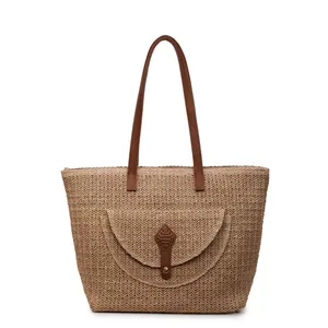 Large woven straw tote bag with brown leather straps and a decorative front pocket