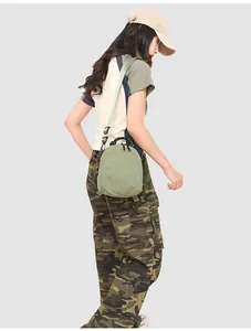 Detail of light green nylon mini bag with rope handle shown on a model in cargo pants