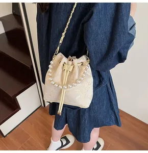 Detail of embroidered butterfly pattern on ivory bucket bag with elegant pearl handle
