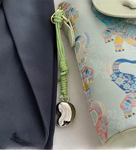 Close-up of green woven mini bag with elephant pattern and silver bean metal charm