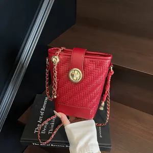 Sac seau tissé rouge chic avec fermoir rotatif doré et bandoulière chaîne en cuir
