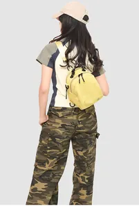 Rear view of vibrant yellow mini canvas backpack worn by model in an outdoor style