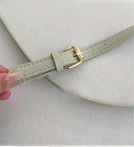 Detail of light green PU leather strap with adjustable gold-tone metal buckle and stitching