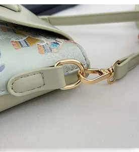 Close-up of golden metal hooks and mint green floral jacquard fabric on the mini crossbody bag