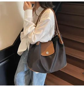 Detail of a large nylon tote bag with leather flap and stitching on a woman's shoulder