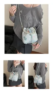Detail of light blue embroidered bucket bag with pearl handle and koi carp motifs