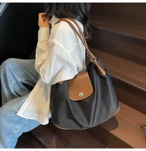 Detail of large nylon tote bag with leather trim and silver metal twist lock closure