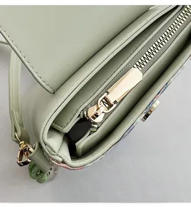 Macro view of smooth gold zipper and hardware on light green PU crossbody phone bag