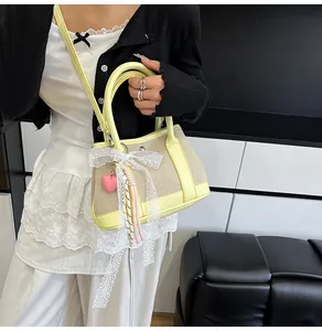 Close-up of beige crossbody bag with yellow leather trim, lace bow, and heart charm