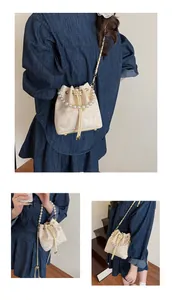 Detail view of cream bucket bag with butterfly embroidery and pearl handle and chain strap