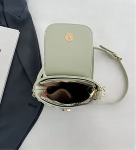 Detail of green mini crossbody bag showing internal compartments and zipper closure
