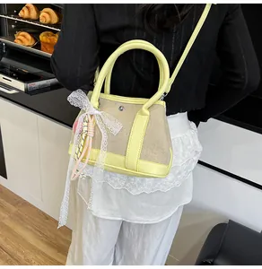 Detail of color-block patchwork handbag with lace bow and woven charm on a model